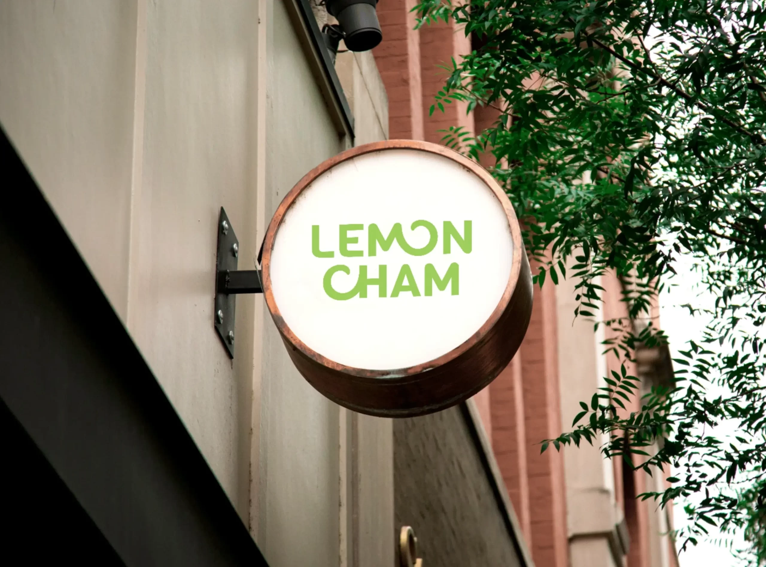 Simulación del diseño de marca LemonCham en un rótulo exterior, mostrando el logotipo sobre una fachada urbana.